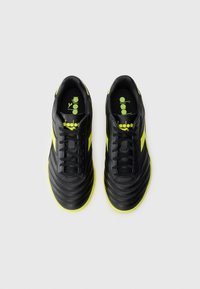 Black soccer shoes with textured leather, lime green accents, and a classic design. Featuring a lace-up closure and padded interiors.