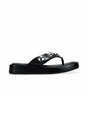 Sandalia tipo flip-flop plataforma negra con tres grandes tachuelas plateadas en la correa y una suela ranurada, mostrada en perfil lateral.