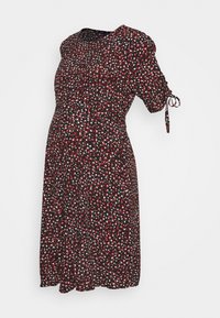 Robe de maternité noire avec un petit motif floral rouge et blanc, encolure ronde et manches courtes avec un détail de noeud.