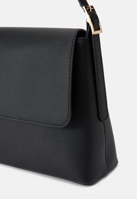 Čierna kabelka s textúrovaným povrchom, štruktúrovaným tvarom, klopňou a zlatými kovovými detailmi na nastaviteľnom popruhu.