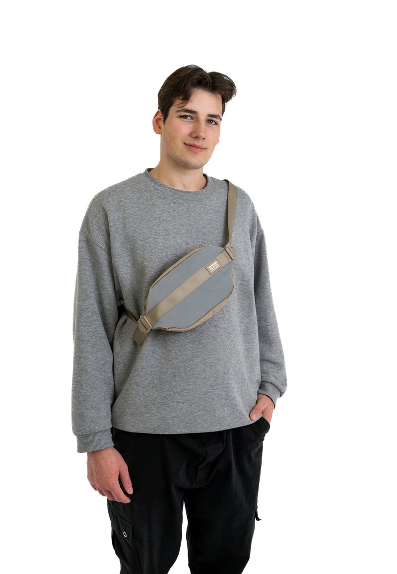 Marsupio grigio dal design elegante, con superficie in tessuto grigio chiaro, dettagli marroni e una tracolla regolabile da indossare sul corpo.