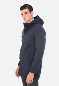 Giacca impermeabile blu navy con cappuccio, zip frontale e due tasche laterali. Caratterizzata da una texture liscia e un design aderente.