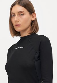 Black long-sleeve top with a slim fit. Features a textured fabric with mesh accents. Displaying a small white logo on the upper chest.