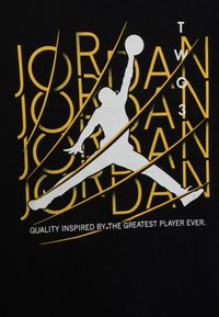 Svart T-shirt med en vit silhuett av en hoppande figur, gul text "JORDAN 23" och frasen "KVALITET INSPIRERAD AV."