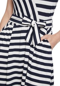 Striped dress in navy and white fabric, featuring a tied belt, flared skirt, and side pockets. The stripes are evenly spaced and horizontal.