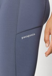 Jūras spēku legingi, kas izgatavoti no stiept auduma, ir ar gludu tekstūru, dekoratīvām šuvēm un mazu pelēku "patagonia" logo sānos.