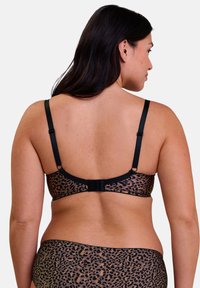 Soutien-gorge à imprimé léopard avec des bretelles noires et une fermeture à crochet au dos. Tissu doux avec un design semi-transparent.