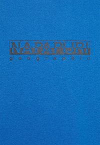 Modrá tkanina s černým textem "NAPAPIJRI" v obdélníkovém rámečku a menším textem "geographic" pod ním.