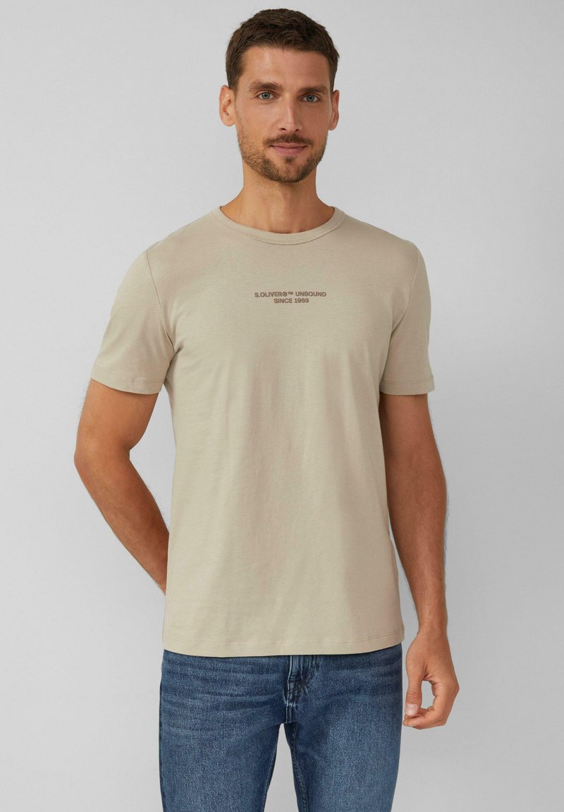 Beige t-shirt met korte mouwen en ronde hals, met de opdruk "S. OLIVER UNBOUND SINCE 1969" in donkerbruin. Gemaakt van zacht katoen.