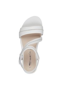 Vit sandal med flera remmar i design, slät material, lätt klack och silvriga accenter på remmarna. Platt fotbädd med varumärkeslogotyp.