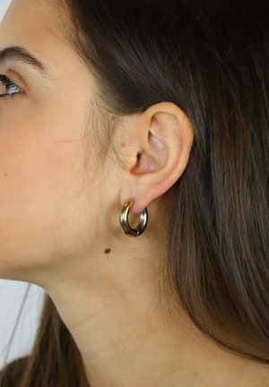 Orecchini a cerchio in metallo dorato e argentato con finitura liscia e lucida. Presentano una forma a mezzaluna robusta e un contrasto di colore distintivo.