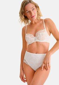 Kanten beha en high-waisted slipset in zacht ivoor, met bloemmotieven en gegolfde bandjes voor een delicate textuur en ontwerp.