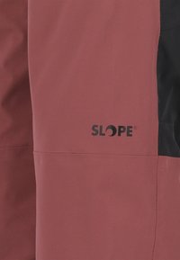 Maroon och svart ytterkläder med slät textur, robust tyg, sydda sömmar och "SLOPE"-logotypen i svart på den maroonfärgade delen.