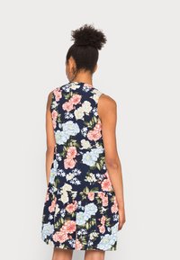 Marinblå blommig klänning med rosa och blå blommor, ärmlös design, lagad fåll och med en mjuk tygtextur.