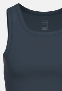 Mörk marinblå tanktopp i ekologisk bomull med rundad ringning, slät textur och platta sömmar, märkt "AMMANN" inuti. Tillverkad i Europa.