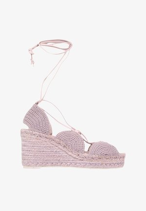 Sandale espadrille compensée avec dessus en crochet rose clair, bords festonnés, semelle plateforme tressée et lacets à nouer autour de la cheville.