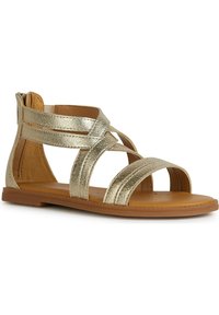 Guldmetalliska sandaler med platta sulor, flera korsande remmar och en slät läderliknande textur. Öppen tå design och baklös stil.