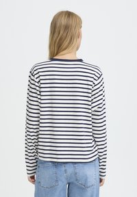 Chemise à manches longues rayée crème et bleu marine. Dotée d'un col rond et d'une coupe décontractée, avec un ourlet droit et des poignets côtelés. Style décontracté.