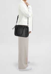 Musta nahkainen käsilaukku, jossa on kaksinkertaiset yläkahvat ja säädettävä olkahihna. Sujuva pinta, minimalistinen muotoilu, jossa on hopeiset yksityiskohdat.