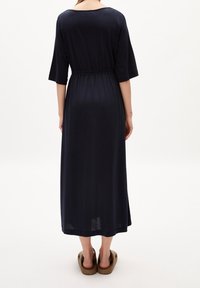 Merisuklaan sininen pitkä mekko pehmeästä kankaasta, jossa rento istuvuus, joustava vyötärö, kolme neljäsosa hihaa ja pyöreä pääntie.