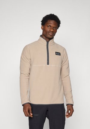 Beige fleece pullover met een hoge kraag, half-rits sluiting en zwarte accenten. Beschikt over een borstlogo patch en contrasterende afwerking op de manchetten.
