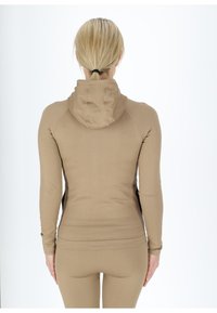Braune Ripp-Hoodie mit tailliertem Design, langen Ärmeln und Kapuze. Glatte Textur mit leicht dehnbarem Material.