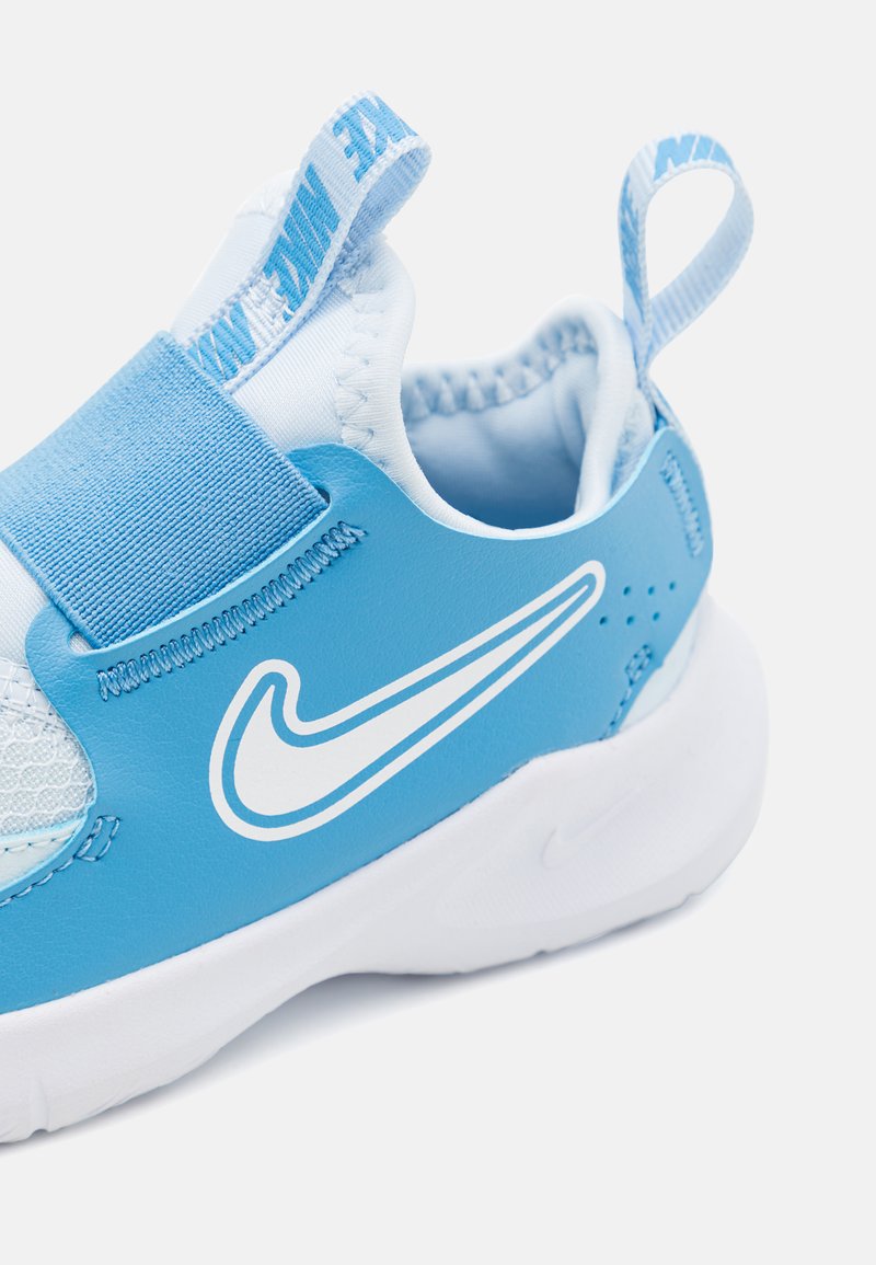 Scarpa sportiva blu con accenti bianchi, dotata di pannello in rete, cinturino elastico e linguetta. Materiale sintetico liscio e suola arrotondata.