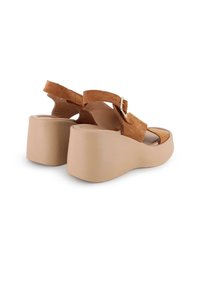 Sandalias de plataforma de ante marrón con suela gruesa color tostado, parte trasera abierta y correa ajustable en el tobillo con hebilla de metal.