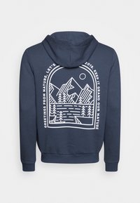 Mörkblå huvtröja med vit grafik av berg och sjö på baksidan, med text: "Hälsningar från naturen, låt oss behålla storheten."