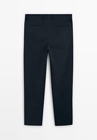 Pantalons noirs sur mesure vus de dos avec passants pour ceinture et deux poches fendues sur un fond uni.