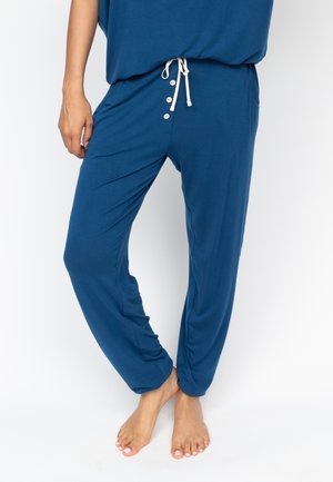 Lichte blauwe broek van zacht materiaal, met een trekkoord in de taille, knopen en zijzakken. Het ontwerp is los en taps toelopend.