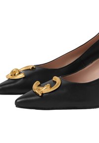 Ballerine in pelle nera con punta affusolata e una prominente fibbia dorata sulla tomaia. Texture liscia e un design di silhouette classica.