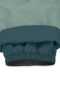 Textil in Türkis mit strukturierter Oberfläche und gesammeltem Bündchen, das einen schwarzen, elastischen Saum hat. Glatte Oberfläche und leichtes Design.