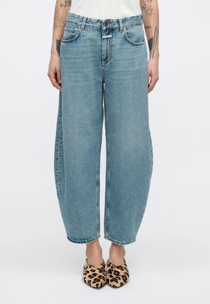 Jean en denim bleu clair à coupe large, légèrement délavé, avec un design classique à cinq poches et des coutures contrastées.