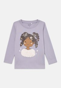 Lilla langermet barnegenser med grafikk av en blinkende jente med mørkt flettehår pyntet med hvite sløyfer og en strukturert hvit topp.