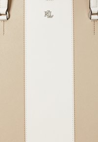 Beige and white structured handbag featuring Saffiano texture, silver logo, and adjustable straps with stitching details.