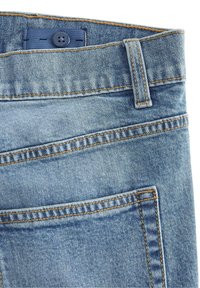 Ljusblå denimjeans med en jämn textur, som har orange sytråd, två framfickor och en knappstängning vid midjan.
