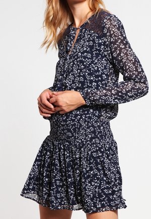 Marineblå kjole med hvidt blomsterprint, lange ærmer, knapper foran, blonder på skuldrene, elastisk talje og skørt med vidde.