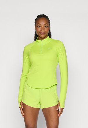 Dugih rukava, svijetlo neonskog zelenog sportskog majicu s okovratnikom na zip, uparenih s odgovarajućim šortsevima s crnim Nike logom.