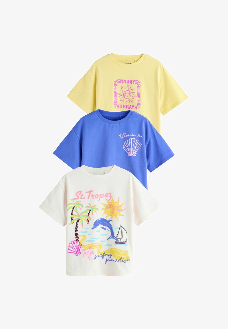 Trzy T-shirty z krótkim rękawem ułożone w stos, żółty z nadrukiem słońca, niebieski z nadrukiem muszli, biały z tropikalną plażą i nadrukami tekstowymi.