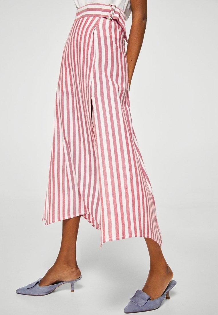 Pantalons larges rayés rouges et blancs avec une taille haute, dotés d'une boucle de ceinture. Tissu doux, ourlet irrégulier et fentes sur les côtés.