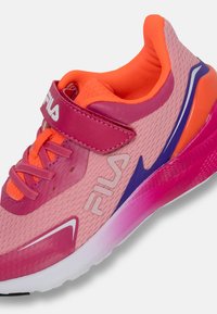 Scarpa sportiva rosa con tomaia in mesh, fodera arancione vivace e dettagli viola a contrasto. Presenta una cinghia regolabile e una suola testurizzata.