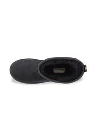 Zapatilla negra con una textura exterior suave, forro interior blando, puntera redondeada y costura de contraste a lo largo del borde.