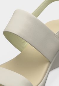 Κοντινό πλάνο μπεζ σανδάλι με ανοιχτά δάχτυλα, φαρδιά λουράκια και πλατφόρμα, σε λευκό φόντο.