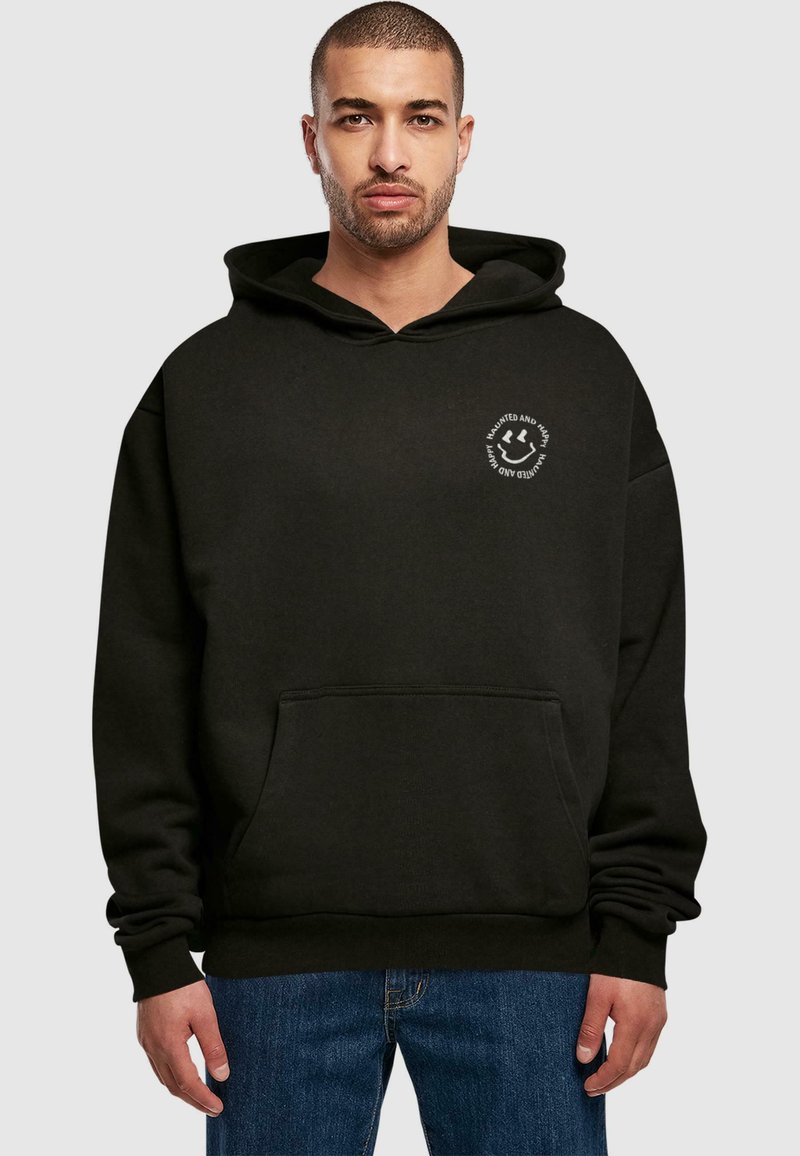 Schwarzer Hoodie mit einer Vorderasche, Kapuze mit Kordelzug und einem runden weißen Logo auf der linken Brust. Mit gerippten Bündchen und Saum.
