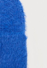 Textil azul difuso con una textura suave y prominente. El material es grueso y tiene un color rico y vibrante, creando una apariencia táctil.