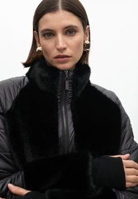 Black puffer jacket with a faux fur collar, featuring a front zipper and ribbed cuffs. Smooth texture with a glossy finish overall.