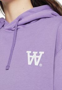 Purple hoodie with a smooth texture, featuring a white logo on the chest area and drawstring at the hood.