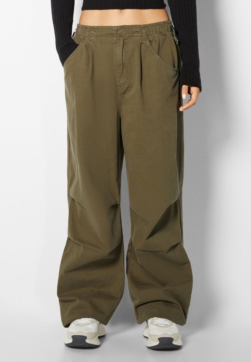 Pantaloni cargo in cotone verde oliva con una vestibilità rilassata, dotati di tasche laterali, una vita elastica e una texture liscia e opaca.