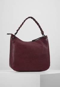 Sac à main en cuir bourgogne avec une finition texturée, une anse tressée et une fermeture zippée. Forme arrondie avec des accents en métal argenté.